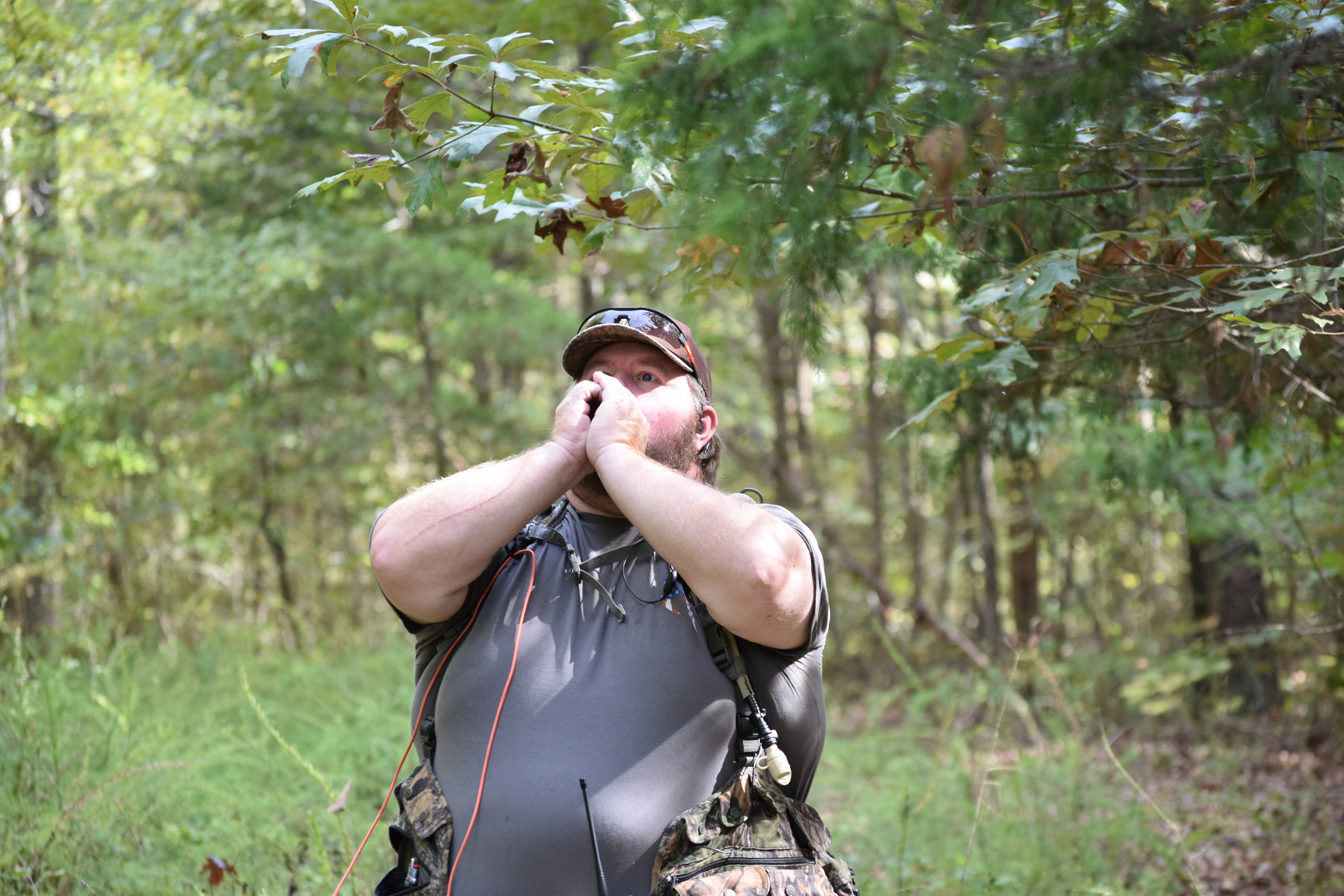 Field researcher with hands cupped near his mouth in a wooded setting
